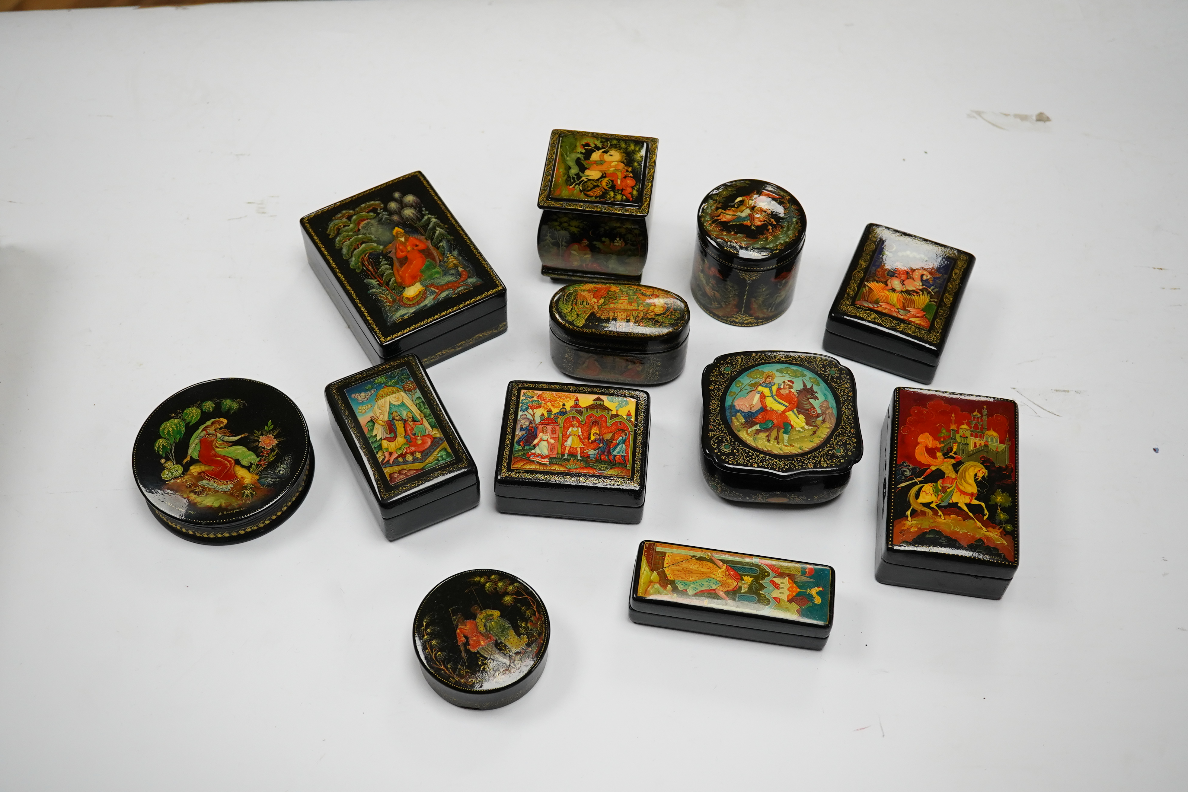 A quantity of Russian lacquer boxes decorated with figures and mythical scenes, largest 10cm in length. Condition - mostly good